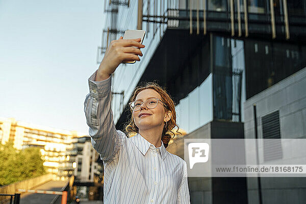 Smiling businesswoman taking selfie through smart phone