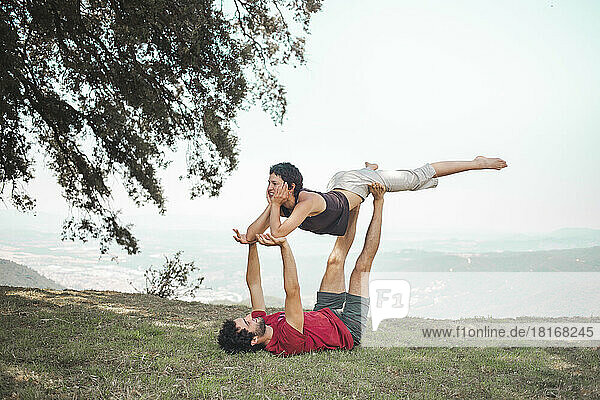 Young man and woman doing acroyoga on top of mountain