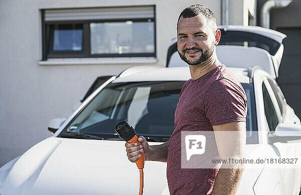 Mid adult man holding charging plug for electric car