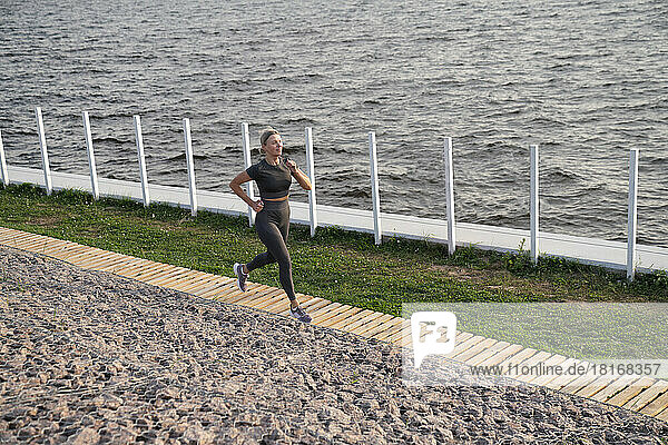 Mature woman jogging on footpath by sea