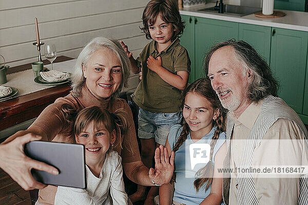 Grandmother with grandchildren taking selfie through tablet PC at home