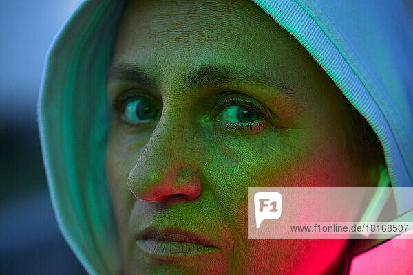 Serious woman wearing hood with reflection of lights on face