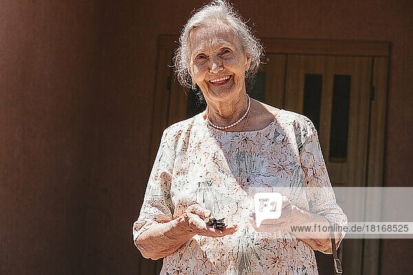 Smiling senior woman with car keys outside house