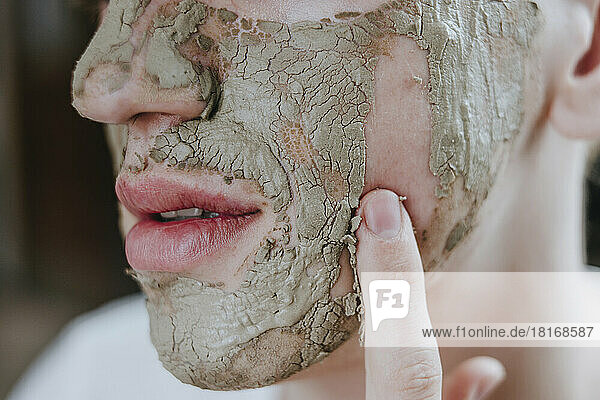 Make-up artist removing facial mask with finger