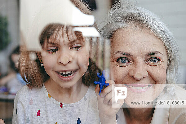 Smiling grandmother with granddaughter seen through window