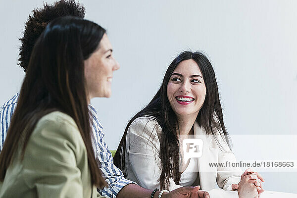 Happy businesswoman looking at colleague in office