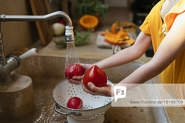 Hände eines Mädchens  das Tomaten in der Küchenspüle wäscht