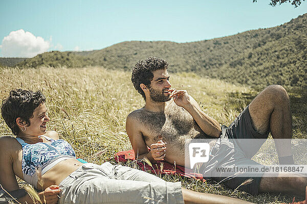 Young couple relaxing on grass at sunny day