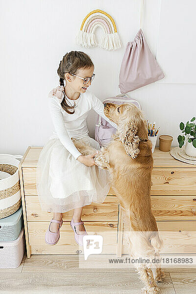Smiling girl playing with dog at home