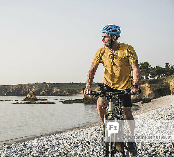 Man wearing cycling helmet riding bicycle at beach