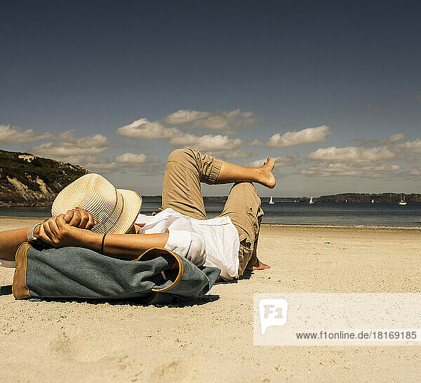 Reife Frau mit Hut entspannt sich an einem sonnigen Tag am Strand
