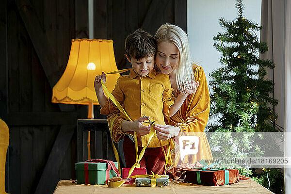 Mutter und Sohn schneiden Band durch  um Geschenk zu binden
