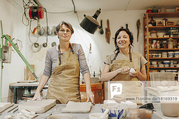 Glücklicher Unternehmer mit Kollegen  die in der Keramikwerkstatt zusammenarbeiten
