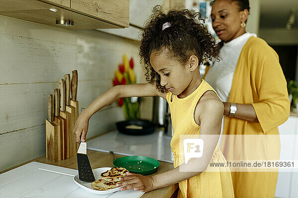 Girl helping mother cooking at kitchen counter