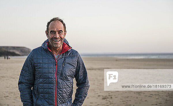 Cheerful mature man wearing jacket standing at beach