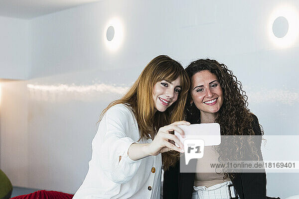 Two happy businesswomen taking a selfie in office