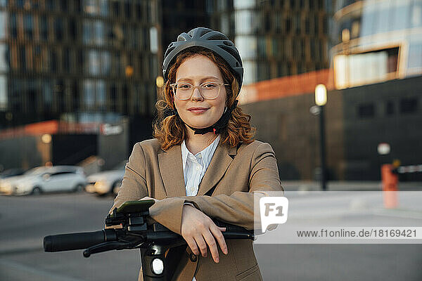 Smiling young businesswoman with electric vehicle