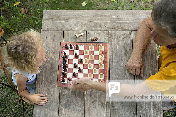 Großvater und Enkelin spielen Schach auf dem Tisch