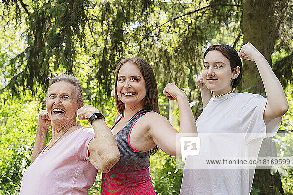 Active senior woman flexing muscles with daughter and granddaughter at park