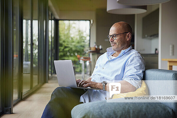 Man using laptop sitting on sofa at home