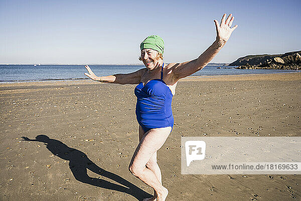 Ältere Frau im Badeanzug hat Spaß am Strand