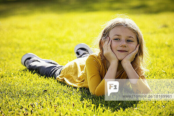 Junges Mädchen  das an einem warmen Herbsttag in einem Stadtpark im Gras liegt und sich ausruht; St. Albert  Alberta  Kanada