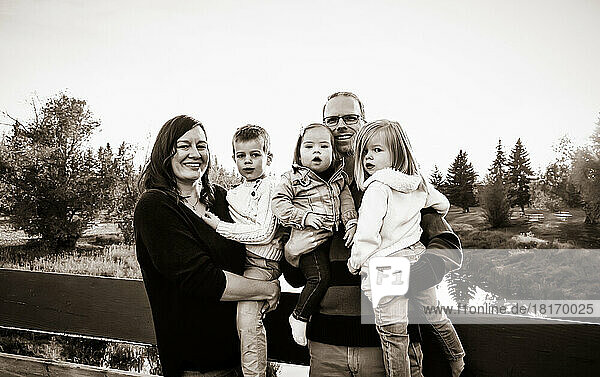 Porträt einer jungen Familie mit drei Kindern  kleine Tochter mit Down-Syndrom  in einem Stadtpark während der Herbstsaison; St. Albert  Alberta  Kanada