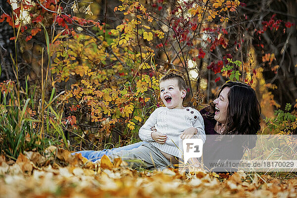 A mother spending quality time and playing with her young son outdoors in a city park during the fall season; Edmonton  Alberta  Canada
