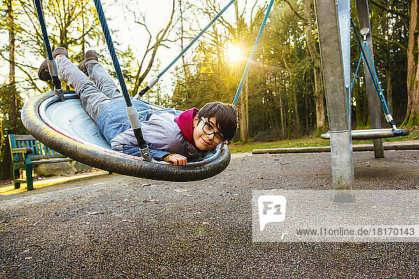 A boy plays on a saucer at a playground in autumn; Langley,  British Columbia,  Canada