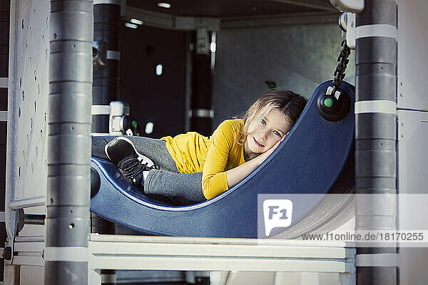 Young girl hiding in a playground apparatus on a warm fall day; St. Albert,  Alberta,  Canada