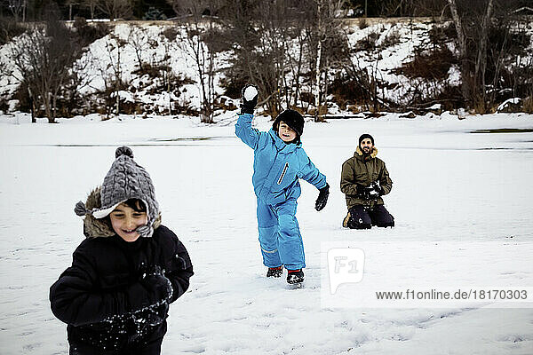 A Father With Two Young Boys Throws Snowballs On A Winter Day At A Mountain Resort; Fairmont Hot Springs  British Columbia  Canada