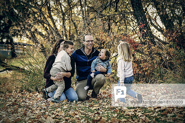 Young family with three children  youngest daughter with Down Syndrome  having fun together in a city park during the fall season; St. Albert  Alberta  Canada