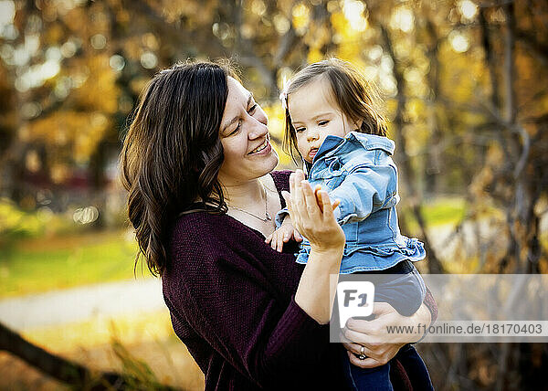 Porträt einer Mutter und ihres kleinen Mädchens mit Down-Syndrom  die während eines Familienausflugs in einem Stadtpark im Herbst viel Zeit im Freien verbringen; St. Albert  Alberta  Kanada