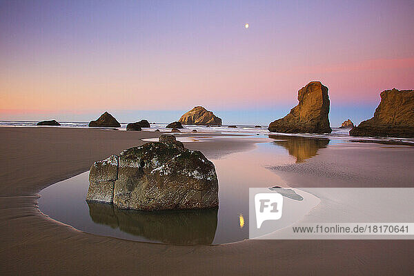 Monduntergang über Felsformationen  die sich in Gezeitentümpeln bei Ebbe in der Bandon State Natural Area an der Küste von Oregon spiegeln; Bandon  Oregon  Vereinigte Staaten von Amerika