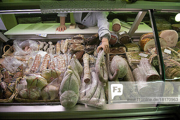 Woman arranges goods in a deli meat case in Locana  Italy; Locana  Italy