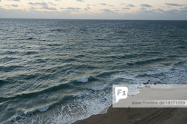 A man walks along the beach of the Florida Coast; Palm Beach  Florida  United States of America