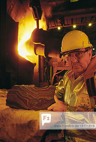 Arbeiter mit scharfkantigem Holz und einer Ofenflamme in einem Stahlwerk
