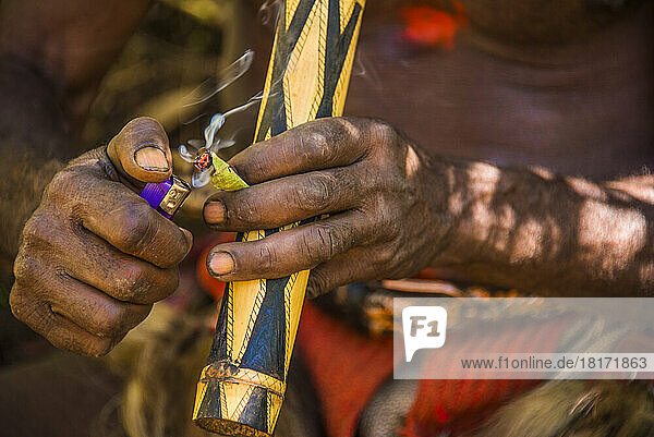 Ein Lehrer der Tigibi-Wigman-Schule im Tari-Tal zündet eine Pfeife an. Junge unverheiratete Huli-Männer besuchen die Schule 18 Monate lang. Sie lernen  ihr Haar wachsen zu lassen  es dann zu schneiden und aus dem Haar eine Perücke zu machen  die sie dann verkaufen; Tigibi  südliches Hochland  Papua-Neuguinea