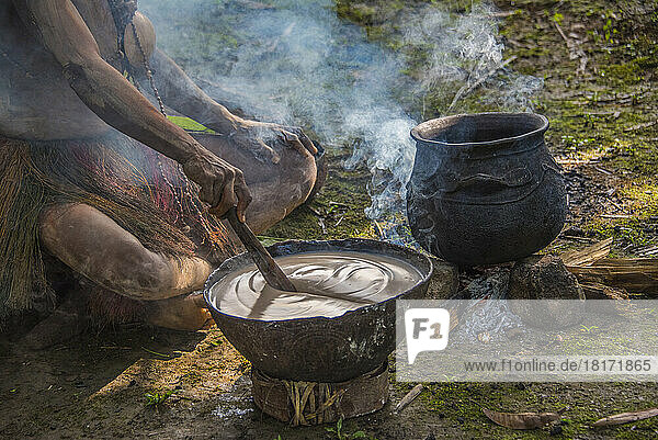 Rühren einer Speise aus Sago in Karawari,  in der Sepik-Region von Papua-Neuguinea. Sago wird in Form von Mehl hergestellt,  das normalerweise aus der Palme gewonnen wird. Sago ist ein gängiger Bestandteil der Küche Papua-Neuguineas,  da die Stärkezutat in mehreren traditionellen Gerichten wie Pfannkuchen und Pudding enthalten ist; Sepik,  Papua-Neuguinea
