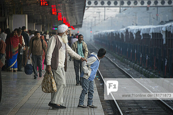 Ein älterer Mann hält ein Kind vor den Zuggleisen in Chandigarh  Indien  zurück; Chandigarh  Neu-Delhi  Indien