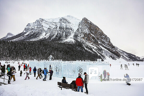 Visitors at Lake Louise skating and looking at the ice castles with Fairview Mountain in the background in Banff National Park; Lake Louise  Alberta  Canada