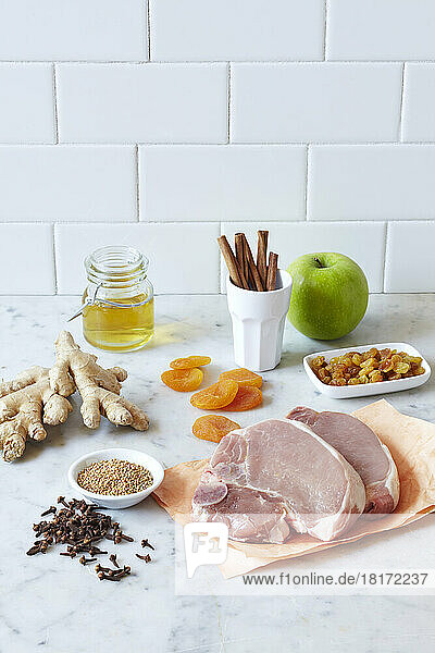 Pork chop dinner ingredients on a marble countertop with white tiled kitchen backsplash