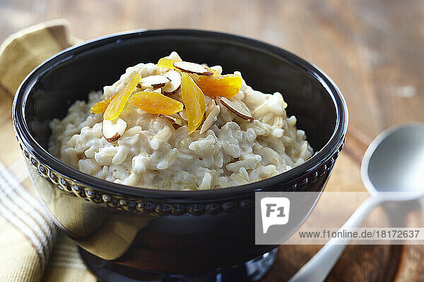 Single Serving Bowl of Brown Rice Pudding with Slivered Almonds and Dried Apricots with Spoon