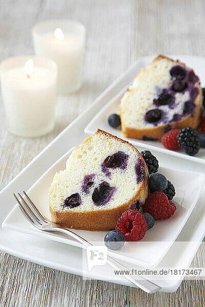 Vanilla bundt cake with mixed berries on white plate with a fork