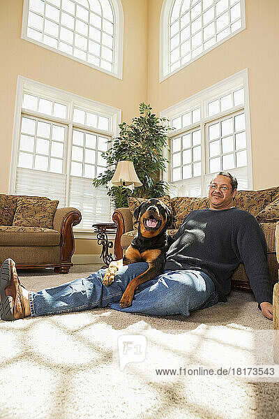Portrait of Mature Man with his Pet Rottweiler in Living Room