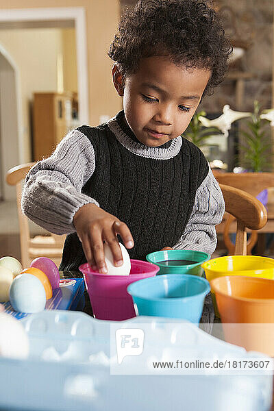 Boy using Coloring Cups to Dye Easter Eggs in Kitchen