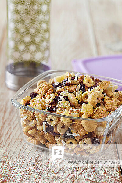 Healthy snack mix in a portable glass storage container with a water bottle
