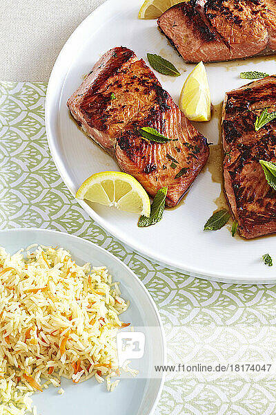 Ginger soy salmon with rice served with fresh mint and lemon wedges