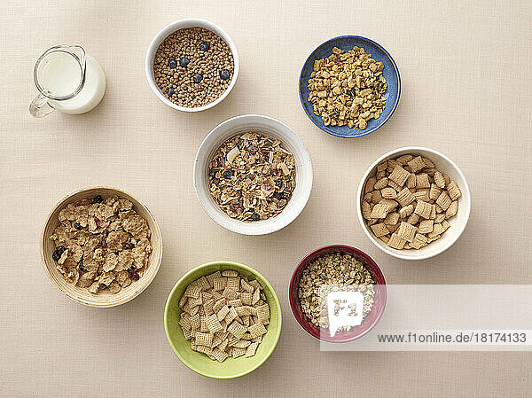 Overhead view of bowls of a variety of healthy cereals and jug of milk  studio shot