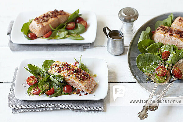 Salmon fillets with spinach and tomato salad on dinner plates